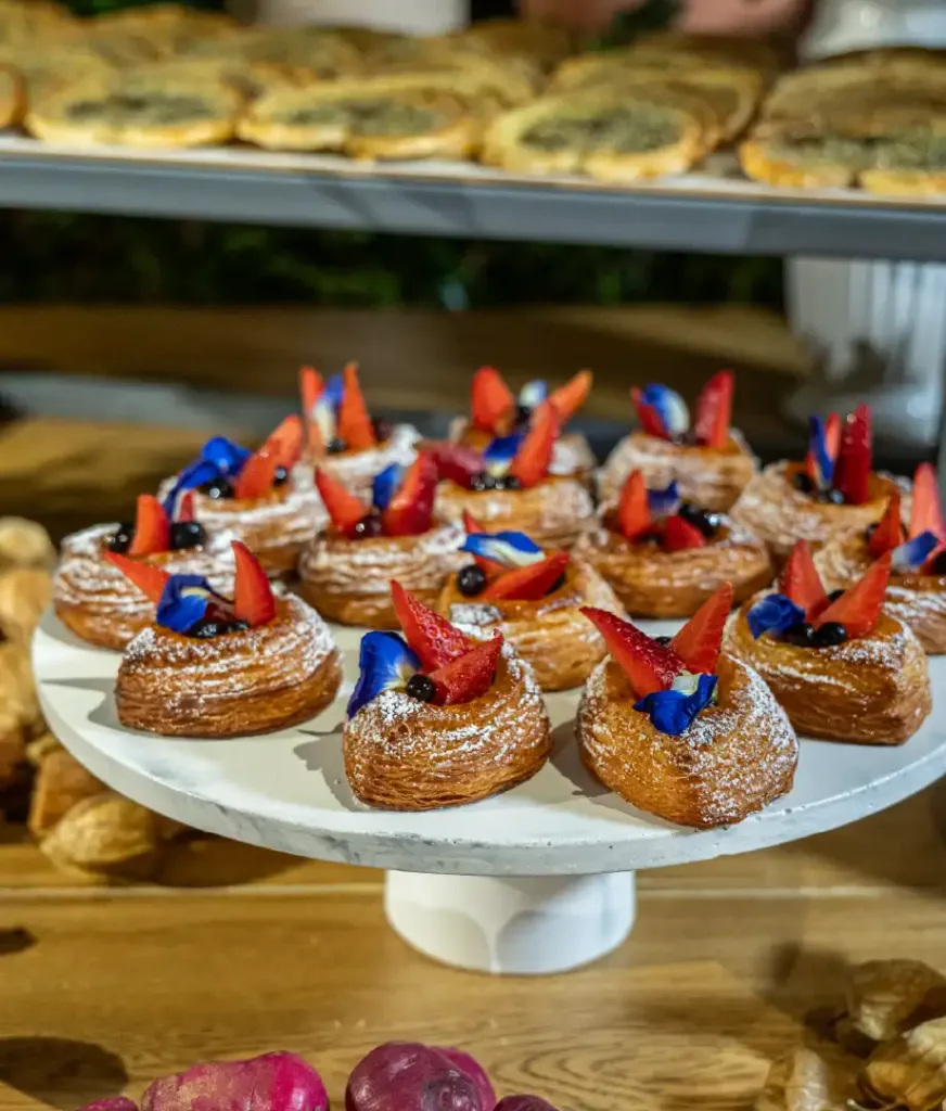 Artisan pastry catering display with Colombian fruit toppings and edible flowers by Nía Bakery, event catering in Cartagena