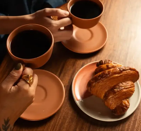 Friends sharing coffee and fresh croissant at Nía Bakery French bakery and coffee shop Cartagena