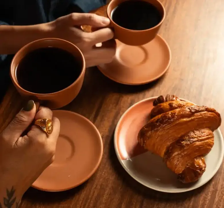 Friends sharing coffee and fresh croissant at Nía Bakery French bakery and coffee shop Cartagena