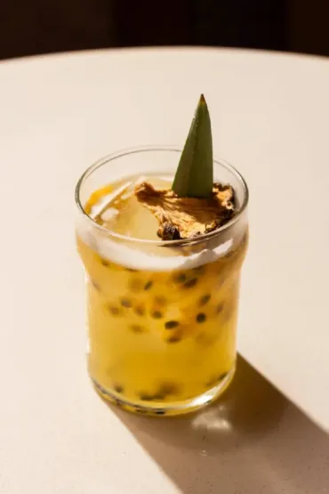 Cóctel de maracuyá con espuma y decoración de hoja tropical en Nía Bakery Coffee Shop & Cocktails Cartagena Colombia